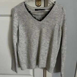 Stickad tröja  - En grå stickad tröja med svart spets 