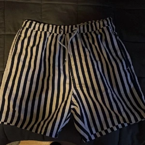 Badbyxor från Bruun & Stengade  - Säljer mina blåvit randiga badbyxor från trendiga märket Bruun & Stengade.  De är helt oanvända, köpte under våren och hann bli försmå till sommaren. Storlek S Nypris 400:- 