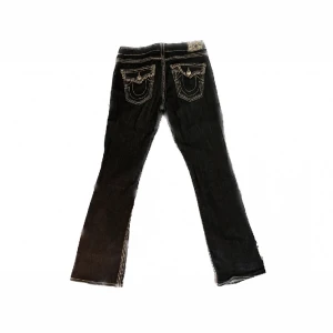 Vintage true religion jeans med ljusrosa stygn! - Ett par superfina vintage true religion jeans som tyvärr inte passar mig längre!! Hör av dig för fler bilder. Färgen är en mörk denim med ljusrosa stygn på sidor och vid fickor!🥰💞säljer för lika mycket som jag köpte för! Midja: 82cm, innerben: 78cm