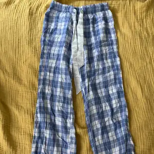 Blå/vit/rosa rutiga pyjamasbyxor. Jätteliten fläck på benet (bild 2), försvinner nog i tvätten. 