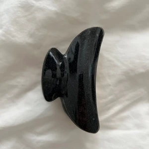 Hårklämma  - Svart glittrig hårklämma med en guld/silvrig färg på insidan.