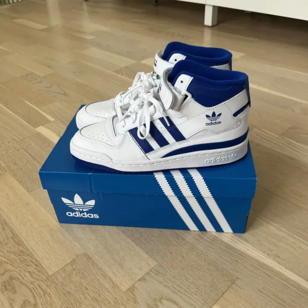 Ett par Adidas forum mid skor i blå o vitt  Nyskick Nypris 1399 . Skor.