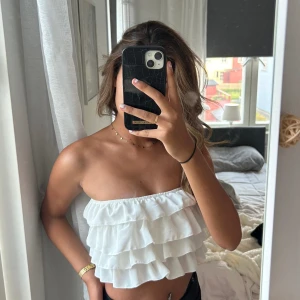 Vit volang topp - Vit bandaue med volanger i storlek XS.  Fin till sommaren. Nytt skick och oanvänd. 