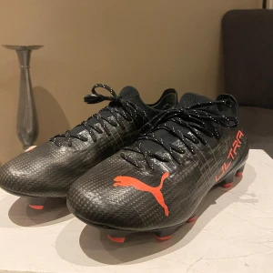 PUMA Ultra 1.3 FG/AG Eclipse - Fotbollskor använda under 5 träningspass. Säljer pågrund av att det inte passade min häl därefter har det lite slitningar i hälområdet (se bild), annars är det som i nyskick.  Ordinarie pris från Unisport 2299kr.  Köpare står för frakt. 
