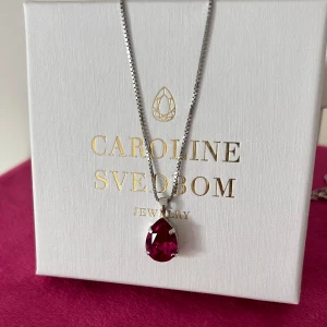 Nytt Caroline Svedbom halsband  - Nytt halsband från Caroline Svedbom i modellen Mini Drop. Oanvänt, i ny/utmärk skick. Storlek: Droppe 14 x 10 mm, längd 50 cm. Plätering:  Rodium. Stenfärg: Fuchsia/ mörk rosa. Ask medföljer. Nypris: 795 kr. Den här färgen är slutsåld