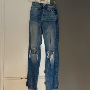 Högmidjade jeans  - Fina jeans med hål vid knäna.  Gått hål i baksidan på båda benen vid ankeln. 