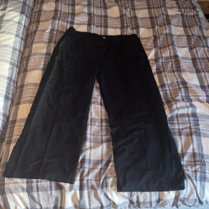Kostym byxor - Svarta kostymbyxor med fickor fram med en synlig söm på benen har ett snöre vid midjan så kan spännas in