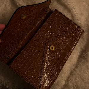 brunt lackad clutch - Otroligt fin brunt lackad clutch. Perfekt att bära små saker i och göra outfiten lite roligare! 
