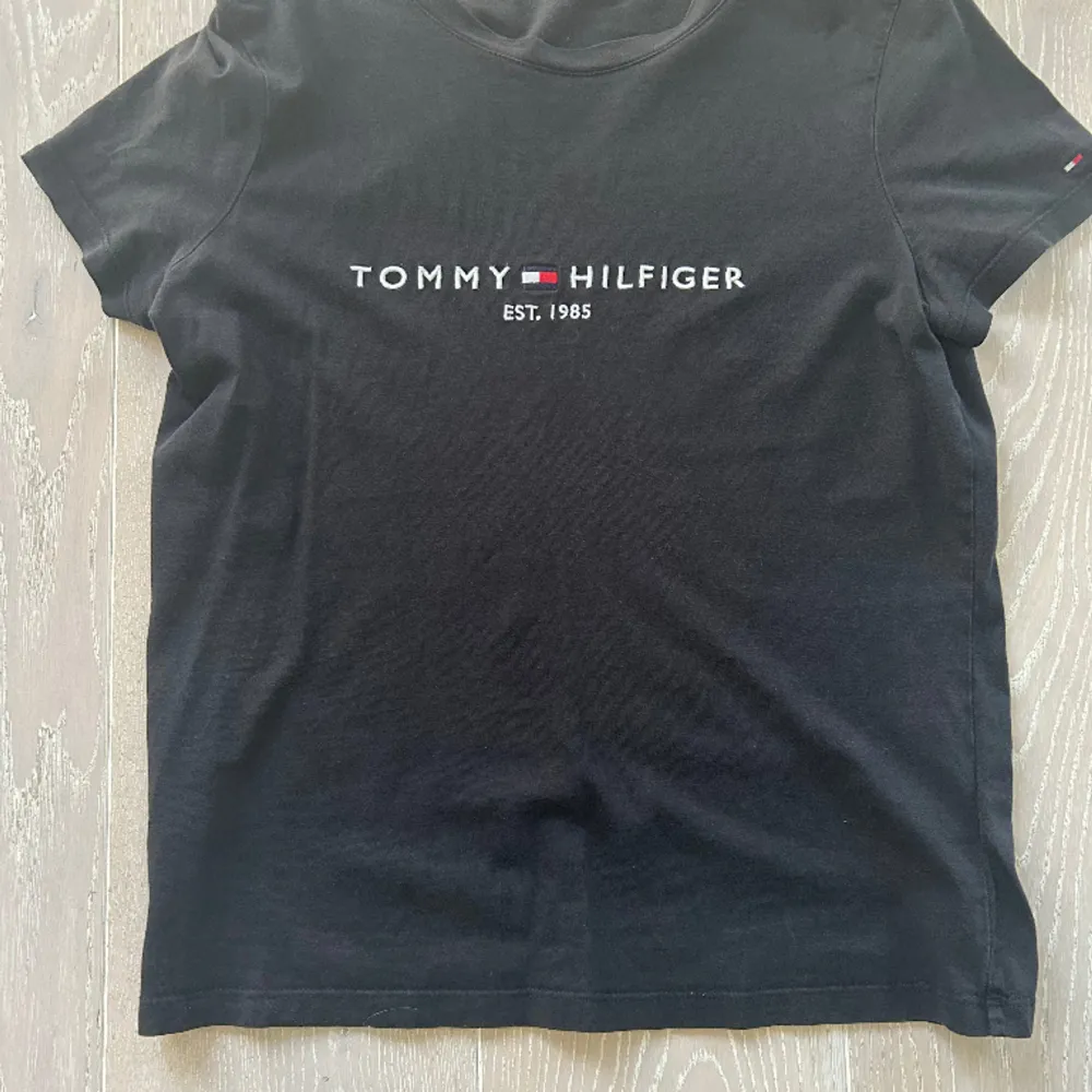 En t-shirt från märket Tommy hilfiger i svart färg, tröjan är för liten för mig därför den ser liten ut på bilden. T-shirts.
