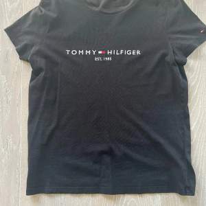 En t-shirt från märket Tommy hilfiger i svart färg, tröjan är för liten för mig därför den ser liten ut på bilden