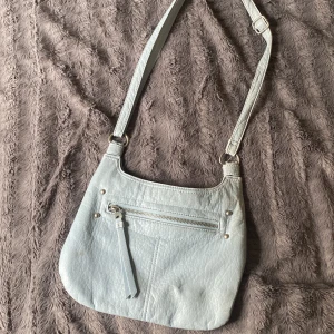 Väska - Fin blå axelväska med anpassningsbart axelband. Har ett stort fack med ett mindre i och även ett på utsidan. Väldigt rymlig och får plats med mer än vad man tror