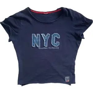 Blå NYC baby tee med fin design 💙Längd: 47 cm. Byst: 42 cm. Jag har strl S för referens! 
