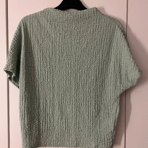 Blus - Denna fina toppen med hög krage i en väldigt fin grön färg. Den är använd endast en gång. Storlek M säljer den för 90kr