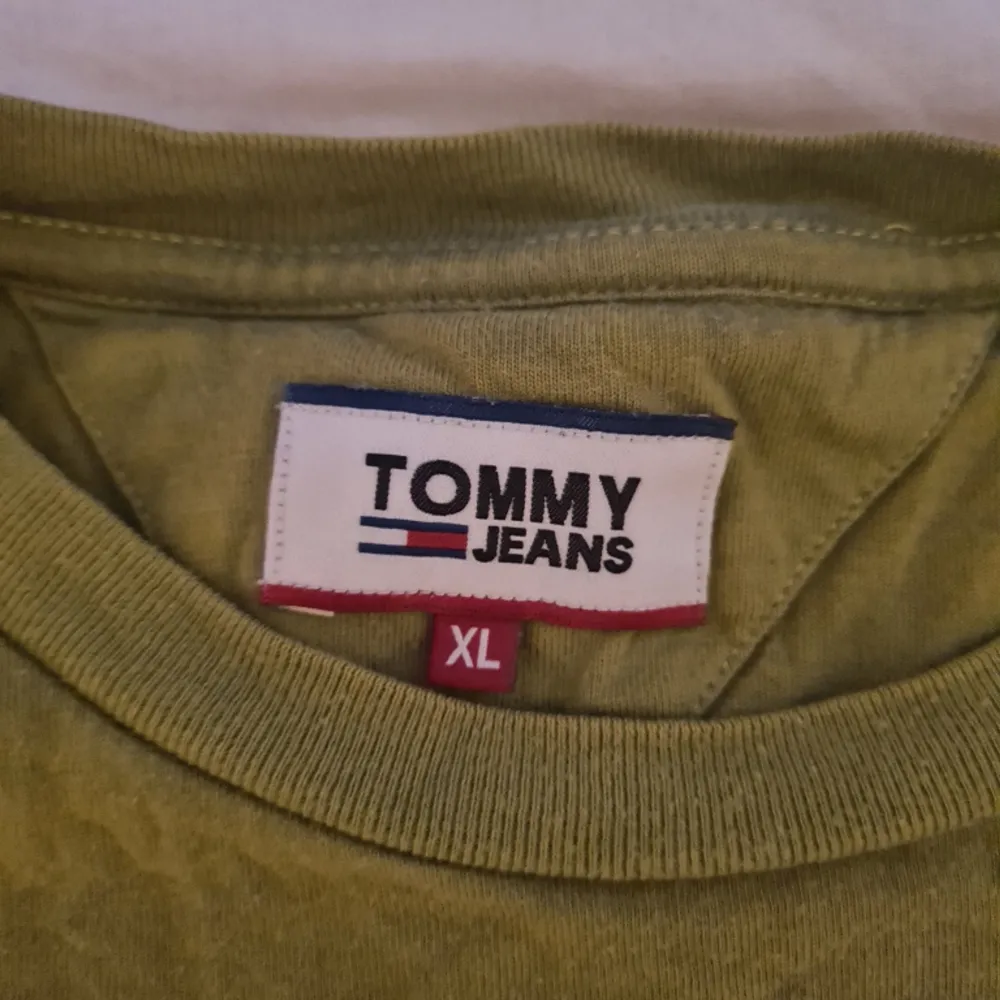 Säljer en Knappt använd Tommy hilfiger tshirt i storlek XL, den är felfri och i nyskick! Färgen är knepig att beskriva men skogsgrön/olivfärgad, som mossa typ.. . T-shirts.
