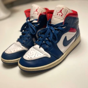 Nike Air Jordans i blått, vitt och rött - Säljer ett par snygga Nike Air Jordans i blått, vitt och rött. Skorna har klassisk snörning och är i mycket bra skick. Perfekta för både vardag och andra tillställningar. De är bekväma och stilrena, en klassiker för alla sneakerheads. Har använt de en sommar och är använd som man kan se på bilderna. Jag har köpt dem på Zalando för ungefär 1400 kr därför säljer jag de för halva:) Alltså är de äkta👍🏼🙂