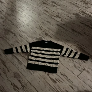 Svart och vit randig tröja från Gina Tricot - Säljer en snygg svart och vit randig tröja från Gina Tricot. Den är perfekt för både höst och vinter med sina långa ärmar och mjuka material. Tröjan har en klassisk design med breda ränder och en bekväm passform. Perfekt för en stilren vardagslook!