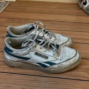 Vita Reebok Classic sneakers - Säljer ett par vita Reebok Classic sneakers i bra skick. De har en retro stil med gröna detaljer och snörning. Perfekta för vardagsbruk och ger en skön vintage vibe. Lite slitna men fortfarande snygga och bekväma.