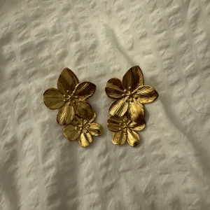 Guldblommiga örhängen - Säljer ett par fantastiska guldörhängen formade som blommor. De har en vacker, detaljerad design med flera lager av blomblad som ger en elegant och unik look. Perfekta för att piffa upp vilken outfit som helst, oavsett om det är till fest eller vardag. 🌼✨
