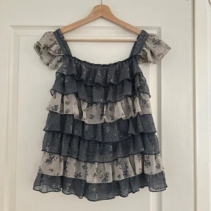 Blommig volangtopp  - Säljer en underbar blommig topp med volanger och axelband. Toppen är i mycket bra skick och ger en romantisk och luftig känsla. Märket är Milla. 