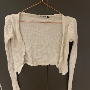 Vit ribbad kofta från Madlady - Säljer en superfin vit ribbad kofta från Madlady. Den är croppad och har långa ärmar, perfekt för lager på lager-stilen. Koftan är i mycket bra skick och passar perfekt till både vardag och fest. Skön och stilren, ett måste i garderoben! 💫