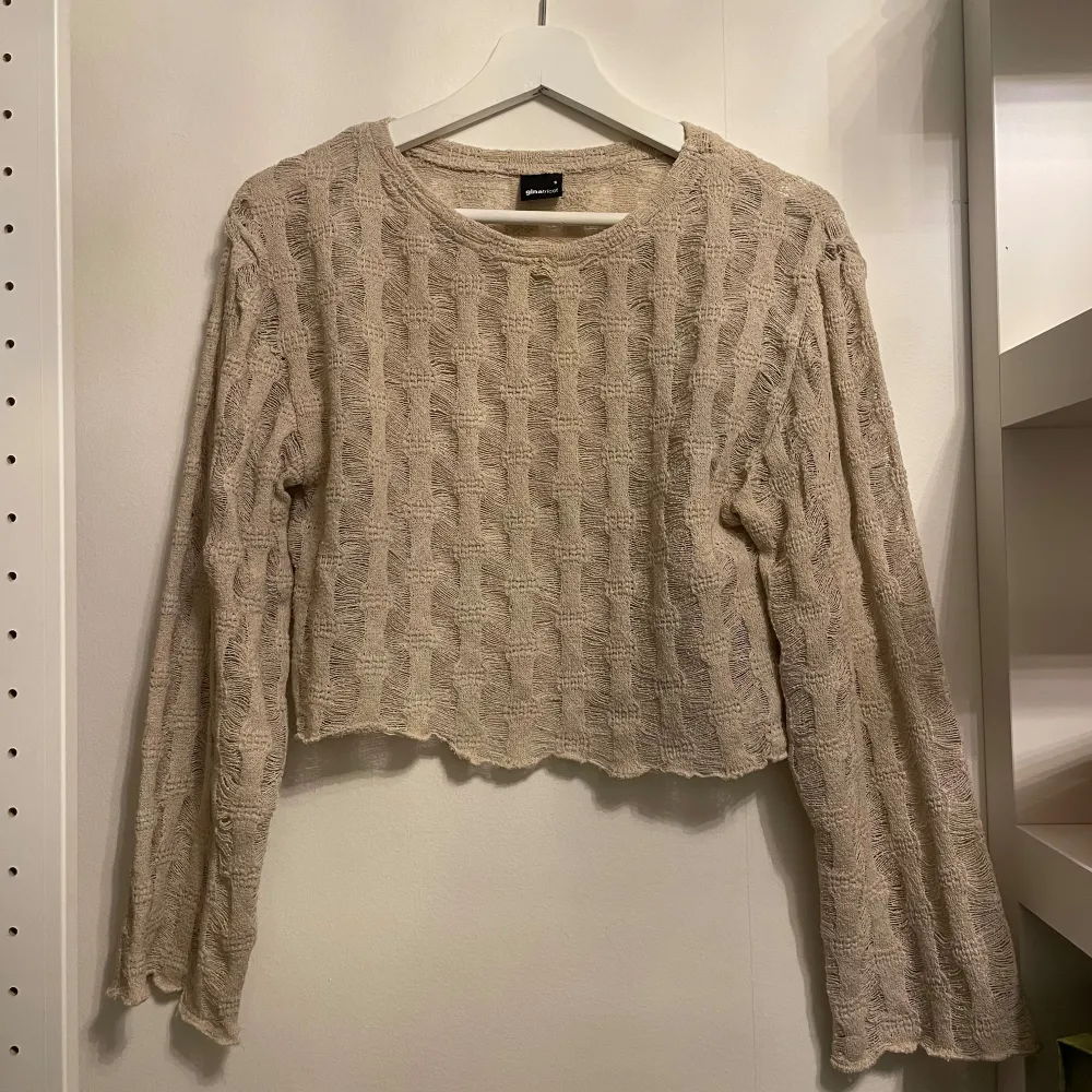 Säljer en superfin beige stickad tröja från Gina Tricot. Den är croppad och har ett snyggt mönster som ger en extra touch. Perfekt för höst och vår! Tröjan har långa ärmar och är i mycket bra skick. Passar perfekt till ett par jeans eller kjol.. Tröjor & Koftor.