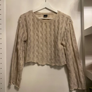 Beige stickad tröja från Gina Tricot - Säljer en superfin beige stickad tröja från Gina Tricot. Den är croppad och har ett snyggt mönster som ger en extra touch. Perfekt för höst och vår! Tröjan har långa ärmar och är i mycket bra skick. Passar perfekt till ett par jeans eller kjol.