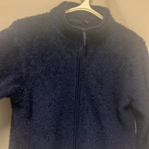 Mörkblå teddyjacka från Uniqlo - Mysig mörkblå teddyjacka från Uniqlo i storlek 160. Perfekt för kyliga dagar med sin fluffiga och varma design. Jackan har en dragkedja framtill och är långärmad. Passar både till vardags och för mysiga stunder hemma. 🧥💙