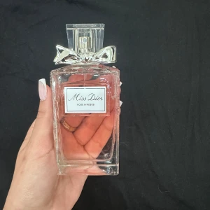 Miss Dior Eau de Parfum - Säljer en elegant flaska Miss Dior Eau de Parfum. Flaskan är genomskinlig med en söt liten rosett på korken. Perfekt för den som älskar en blommig och fräsch doft. Passar både till vardags och fest. Flaskan är nästan full, så det är mycket kvar att njuta av! 🌸