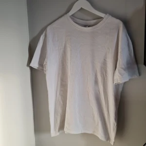 Vit t-shirt från Urban Classics - Säljer en klassisk vit t-shirt från Urban Classics i storlek S. Den är i bra skick och perfekt för vardagsbruk. Skate stil T-shirten har en normal passform åt losse fit hållet. Tjockare tyg, så man ser inte igenom. Enkel och stilren design som passar till allt!