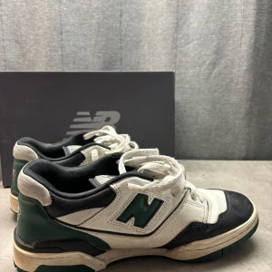 New Balance 550 sneakers - Säljer ett par New Balance 550 sneakers i mycket bra skick. Skorna är vita med svarta och gröna detaljer, och har klassisk snörning. Perfekta för både vardag och träning. Kom gärna med prisförslag