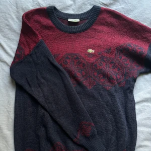 Vintage Stickad Lacoste Tröja - Öppen till prisförslag Vintage Made In France* röd och blå Lacoste lång stickad tröja i ull och akryl, pösig passform Flitigt använd med en mindre märkvärdig defekt (litet hål i arm, se bild) och naturliga defekter som kommer med ålder på stickade tröjor Nypris ca 1800-2000kr, Ärvd