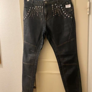 Pulz. Svarta/blå/grå  jeans med nitar - Snygga jeans från PULZ Jeans med coola nitar på framfickorna och bakfickorna. De har Piper loose passform och är perfekta för en rockig look. Jeansen är i bra skick och har en klassisk femficksdesign. Perfekta för både vardag och fest!