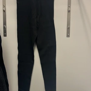Svarta ribbade leggings från H&M Divided - Säljer ett par svarta ribbade leggings från H&M Divided i storlek S. De är superbekväma och perfekta för både vardag och mysiga hemmakvällar. Materialet är stretchigt och ger en tight passform. Passar perfekt till en oversized tröja eller hoodie!