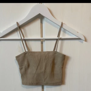 Beige ribbad linnetopp - Snygg beige ribbad linnetopp med smala axelband. Perfekt för sommardagar eller som ett lager under en jacka. Toppen är croppad och ger en trendig look. Passar bra till både jeans och kjol!