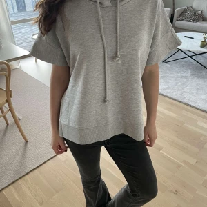 Hoodie  - Säljer en superbekväm grå hoodie med korta ärmar. Den har en avslappnad passform och en cool slits på sidan. 