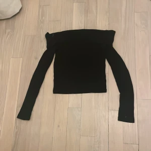 Svart offshoulder tröja - Säljer en stilren svart offshoulder tröja med långa ärmar. Perfekt för både vardag och fest. Tröjan är i bra skick, använd en gång av mig, och trots att den är storlek M passar den även mig med xxs!