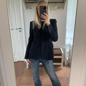 Svart kavaj från Filippa K - Säljer en elegant svart kavaj från Filippa K i storlek small. Kavajen har en klassisk design med knappar framtill och långa ärmar. Perfekt för både vardag och festliga tillfällen. 