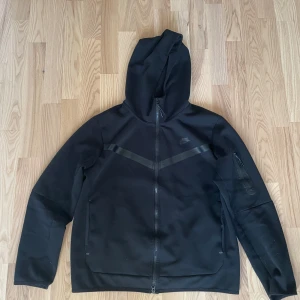 Black Nike tech fleece  - I am selling the black Nike tech that is in perfect condition the pants were only worn once and the hoodie only worn 1-2 months SIZE XL                        Säljer en svart nike tech fleece  i mycket bra skick. Den är i perfekt skick. en praktisk huva. Perfekt för höst och vår, och funkar lika bra till träning som till vardags. Grymt skön och stilren design!
