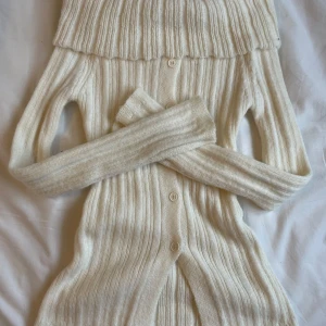 Vit, stickad, ribbad off the shoulder tröja - Säljer en supermysig vit ribbad off the shoulder topp med stora knappar framtill. Köpt i onesize fast passar kanske bäst närmare åt S hållet. Perfekt för kyliga dagar när du vill vara både varm och snygg. Passar till både vardag och fest! 😍💓