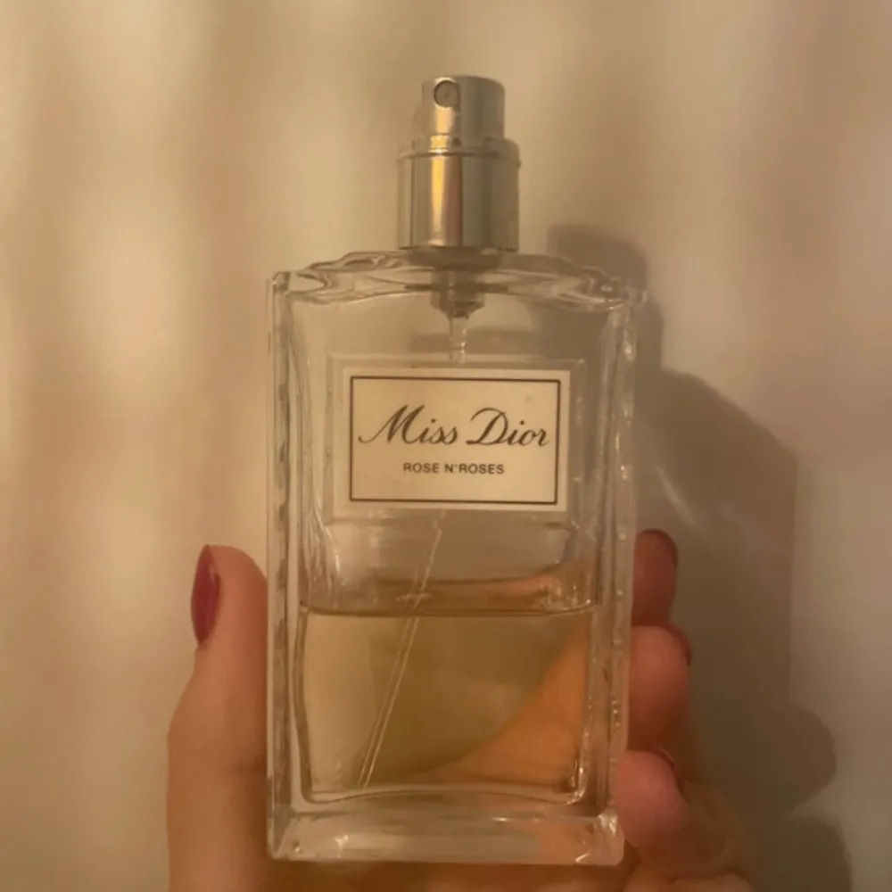 Säljer en elegant Miss Dior Rose N'Roses parfym. Flaskan är stilren och rektangulär med en silverfärgad spraytopp. Doften är blommig och fräsch, perfekt för dagligt bruk. Flaskan är delvis använd men fortfarande mycket kvar. Passa på att få denna lyxiga doft till ett bra pris!. Parfym.