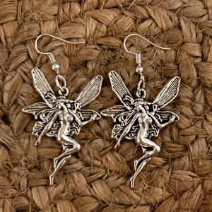 Silverfärgade älvörhängen - Säljer ett par superfina silverfärgade örhängen med älvmotiv. De har en detaljerad design med vingar och en dansande älva. Perfekta för att ge en magisk touch till din outfit! Passar både till vardag och fest. 🧚‍♀️✨