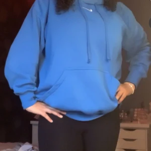 Blå hoodie från Nike - Säljer en snygg blå hoodie från Nike i mycket bra skick. Den har en klassisk känguruficka och justerbar dragsko i huvan. Perfekt för både vardag och träning. Superbekväm och stilren! Köpt för 900kr💙