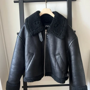 Svart skinnjacka med foder från Zara - Säljer en snygg svart skinnjacka från Zara med mjukt foder. Jackan har en cool krage och dragkedja framtill. Perfekt för höst och vinter! 🖤
