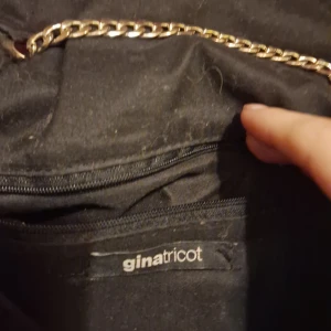 Svart quiltad axelväska från Gina Tricot - Snygg svart quiltad axelväska från Gina Tricot med guldkedja och tofsdetalj. Perfekt för en utekväll eller fest! Väskan har en praktisk dragkedja och magnetknapp för säker förvaring. En metall saknas men den funkar ändå och jag lovar att inget kommer falla ur