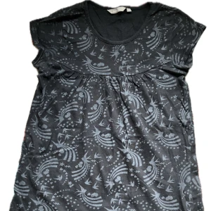 Mönstrad tröja från Lindex - Säljer en svart tröja från Lindex med ett unikt mönster av regnbågar. Tröjan har korta och små ärmar och en rund nacke. 