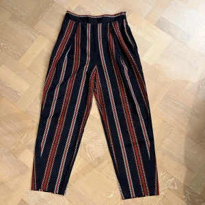 Randiga byxor från Zara - Snygga byxor med ränder i svart, rött och vitt. De har en loose passform och hög midja, vilket ger en bekväm och stilren look. Tunna och lätta!