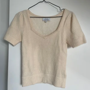 Vit stickad topp från & Other Stories - Säljer en vit  stickad topp från & Other stories med korta ärmar och v-ringad hals. Toppen har ribbade detaljer vid ärmslut och nederkant.