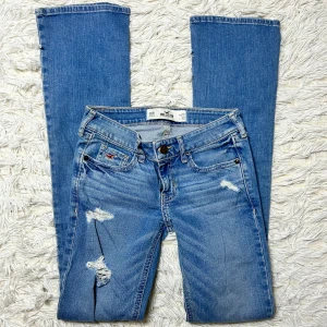 Lågmidjade bootcut jeans med hål Hollister  - Supersnygga hollister jeans med hål i toppen skick. W23L33. Innerbenslängd:81 midjemått: 30 stretch till 33. Har inga bilder på då de är för små/får inte på mig de. Köp sker via köp nu, jag postar inom 24h. Kvar tills markerad såld 