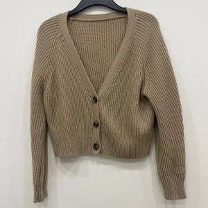 Beige stickad kofta - Säljer en mysig beige stickad kofta med knappar framtill. Koftan har en v-ringad design och långa ärmar, perfekt för kyligare dagar. Den är både stilren och bekväm, ett måste i garderoben! Pris kan diskuteras💞💞