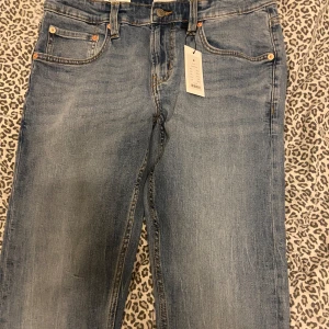 Blå jeansbyxor med raka ben - Snygga blå jeansbyxor med klassisk femficksdesign och raka ben. Byxorna har en knappgylf och är tillverkade i slitstarkt denimtyg. Perfekta för en avslappnad stil.